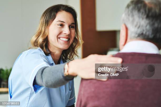 ontsproten van een aantrekkelijke jonge verpleegsterzitting en het binden met haar hogere patiënt in zijn keuken thuis - human hand stockfoto's en -beelden