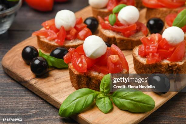 italian bruschetta with tomatoes, mozzarella and black olives and basil. vegan food - milan food stock pictures, royalty-free photos & images