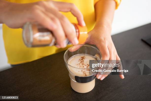 portugal, lisbon, close-up of woman's hands sprinkling coffee with cinnamon - canelo fotografías e imágenes de stock