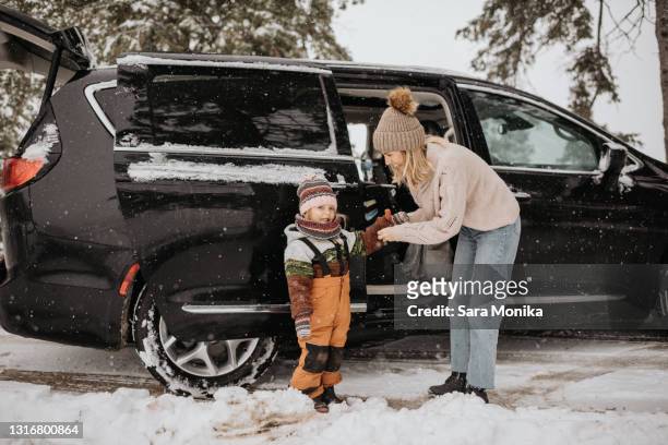 canada, ontario, mother dressing daughter in winter clothes next to car - winter car foto e immagini stock