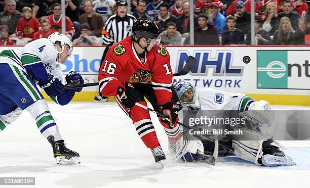 Marcus Kruger of the Chicago Blackhawks gets the puck past Vancouver Canucks goalie Roberto Luongo to score a goal, as Keith Ballard of the Canucks...