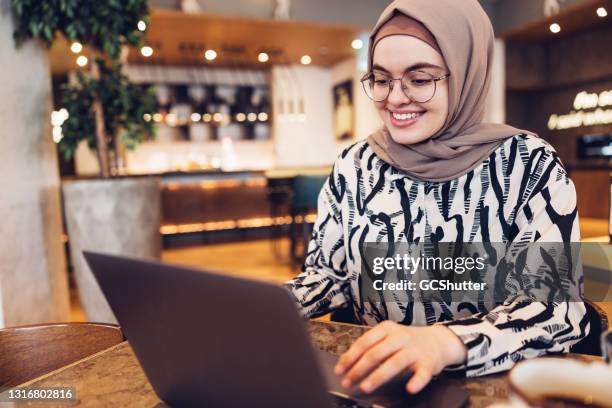 middle eastern female working from a restaurant - arab on computer imagens e fotografias de stock