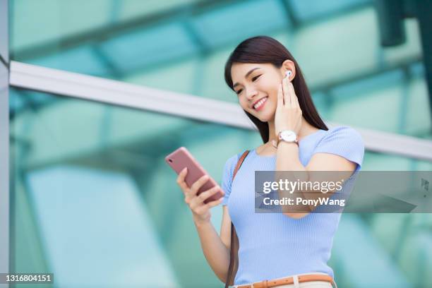 woman use ear buds outdoor - bluetooth earphone chinese stock pictures, royalty-free photos & images