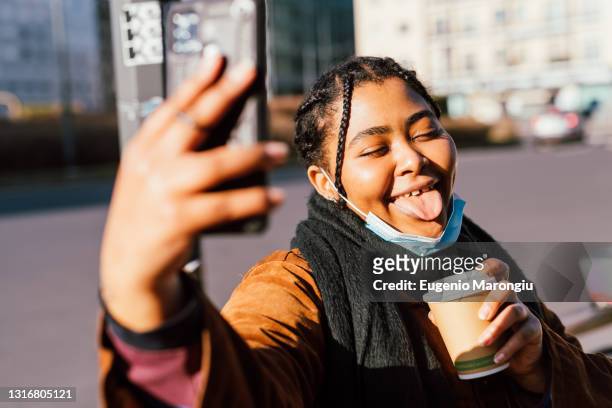 woman sticking out tongue taking selfie outdoors - high sticking stock pictures, royalty-free photos & images