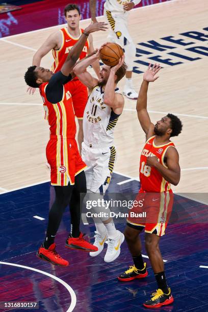 Domantas Sabonis of the Indiana Pacers attempts a shot while being guarded by Onyeka Okongwu and Solomon Hill of the Atlanta Hawks in the first...