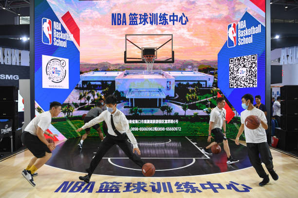 Visitors play basketball at the NBA booth during the first China International Consumer Products Expo at Hainan International Convention and...