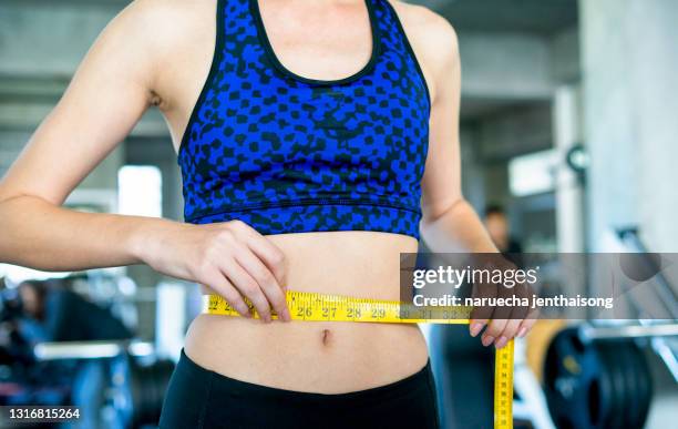 slim young woman measuring her thin waist with a tape measure, close up - woman measuring tape stock pictures, royalty-free photos & images