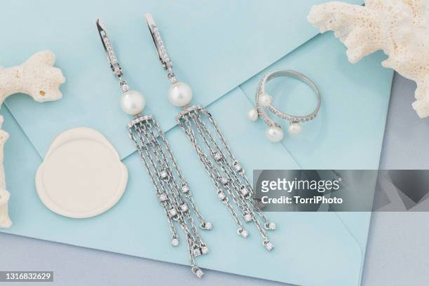 set of silver ring and earrings decorated with pearls on blue envelope background - jeweller stock pictures, royalty-free photos & images