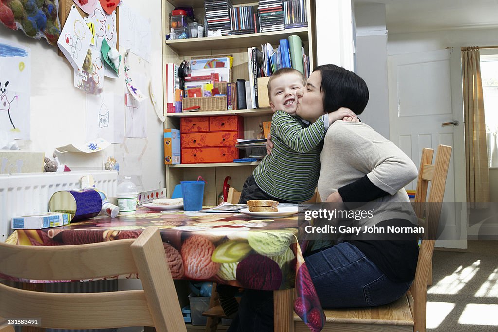 Mum and son hug at kitchen table