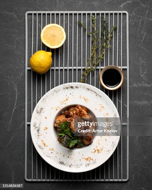 grilled chicken wings with lemon and rosemary. hearty lunch, cooked poultry. top view on black background. vertical format, 4x5 - gourmet chicken stock pictures, royalty-free photos & images