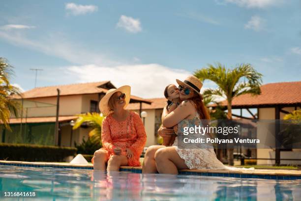 family by the pool hugging the child - moving down to seated position stock pictures, royalty-free photos & images