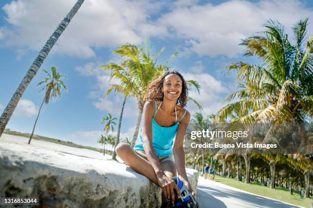 smiling woman putting roller skates - miami beach stock pictures, royalty-free photos & images