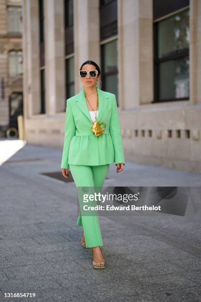 Maria Rosaria Rizzo @lacoquetteitalienne wears large circular earrings, sunglasses, a white top, a pale pastel green gathered blazer jacket, with...
