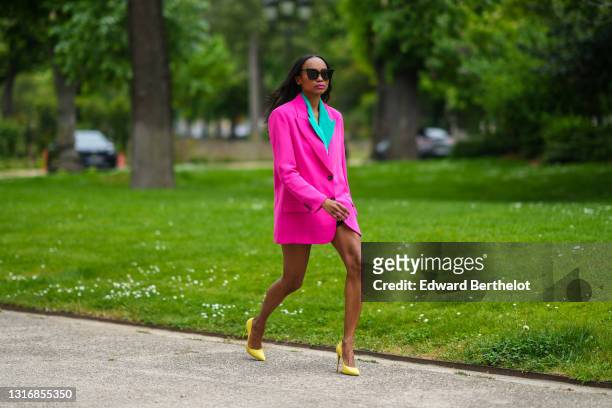 Emilie Joseph @in_fashionwetrust wears sunglasses, a two-tone oversized colorblock blazer in neon pink and green, notched collar, worn as a dress,...