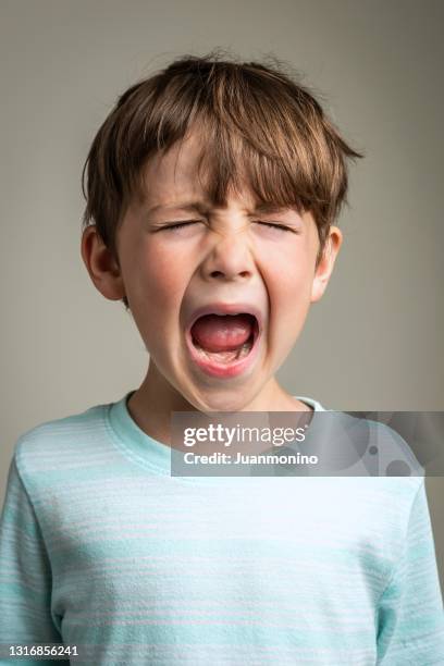 crying caucasian little boy on gray background - crying portrait stock pictures, royalty-free photos & images