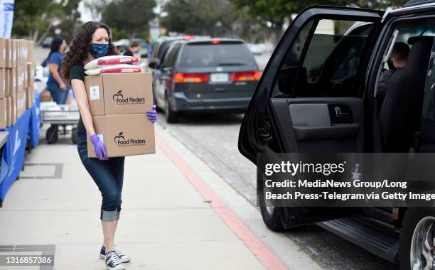 Ilana Elroi carries boxes of food to a car during the SoCalGas"u2019 Fueling Our Communities Event to provide groceries and COVID-19 vaccines at the...