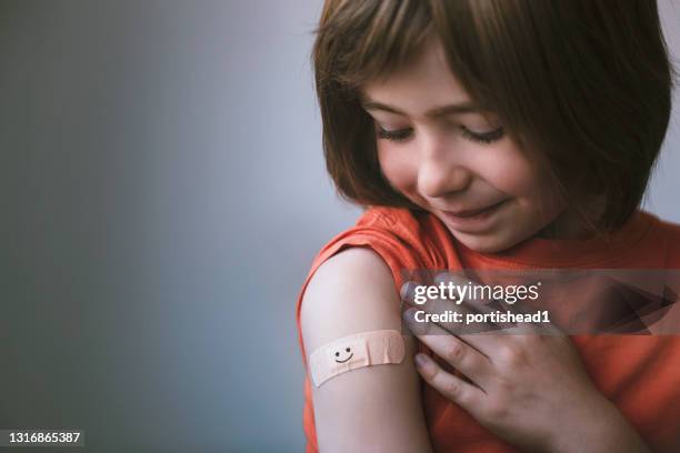 portret van glimlachend weinig kind met zelfklevend verband op zijn hand na vaccinatie - shot stockfoto's en -beelden