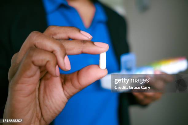 woman holds pill - ibuprofene foto e immagini stock