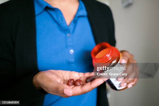 woman holds fruit-flavored multivitamins - gummy snoep stockfoto's en -beelden