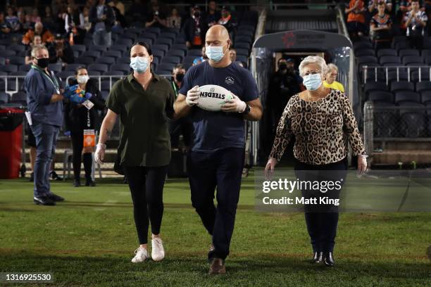Family members of the late Tommy Raudonikis deliver the game ball during the round nine NRL match between the Wests Tigers and the Gold Coast Titans...
