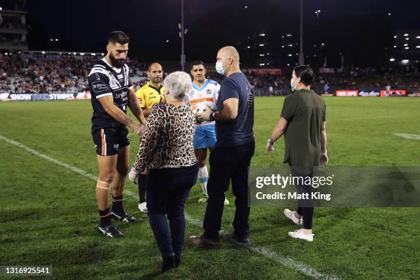 Family members of the late Tommy Raudonikis deliver the game ball to captains James Tamou of the Tigers and Jamal Fogarty of the Titans during the...