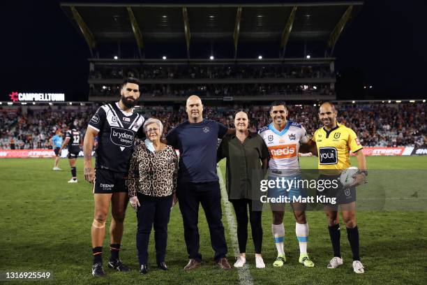 Family members of the late Tommy Raudonikis pose with captains James Tamou of the Tigers and Jamal Fogarty of the Titans during the round nine NRL...