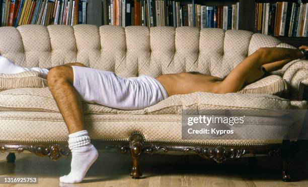 man lying on couch in library room after shower wearing towel around waist and socks - santa monica, california, usa - self assignment archive images stock pictures, royalty-free photos & images