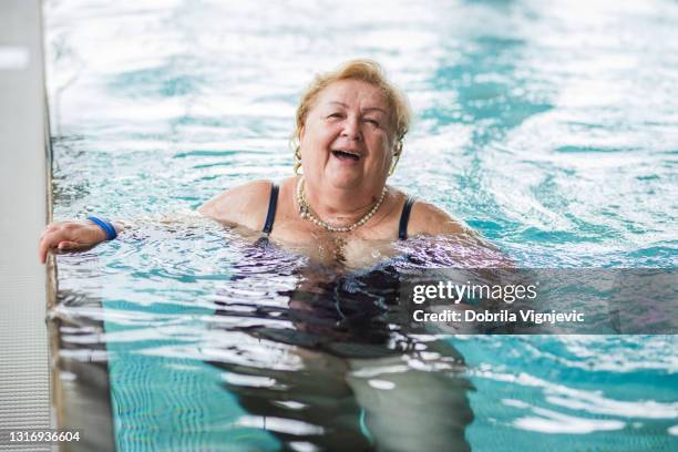 seniorin lächelnd beim gehen im schwimmbad - alte frau badeanzug stock-fotos und bilder