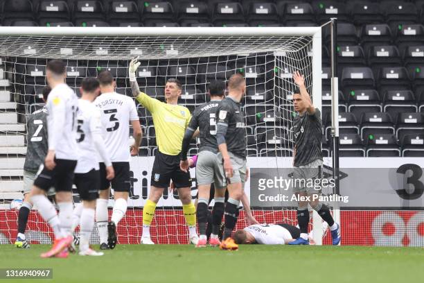 Martyn Waghorn of Derby County lies injured after a collision with the post as Keiren Westwood and Joey Pelupessy of Sheffield Wednesday gesture for...