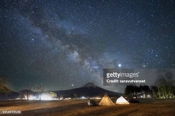 illuminated tents with mt fuji in the distance below the milky way, honshu, japan - キャンプ 夜 ストックフォトと画像
