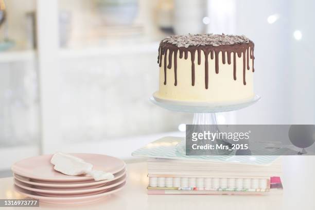 vanilla birthday cake with chocolate ganache, glaze,  on a cake stand in a  kitchen - cakestand stock-fotos und bilder