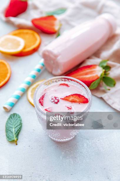 glass and bottle of strawberry yogurt milk shake with fresh strawberries on a table next to ingredients - yoghurt pot stock-fotos und bilder