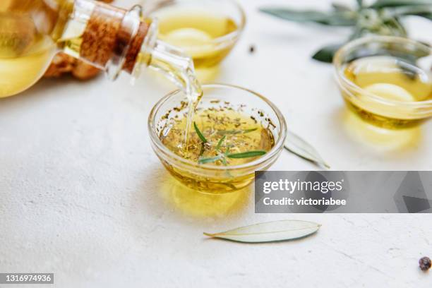 olive oil being poured into a pot with rosemary and oregano - oregano stock pictures, royalty-free photos & images