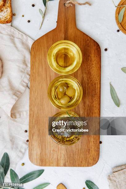 overhead view of three different pots of olive oil with olives and seasoning - olive oil bowl stock pictures, royalty-free photos & images