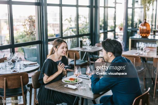 man giving anniversary gift to her partner - dinner date stock pictures, royalty-free photos & images