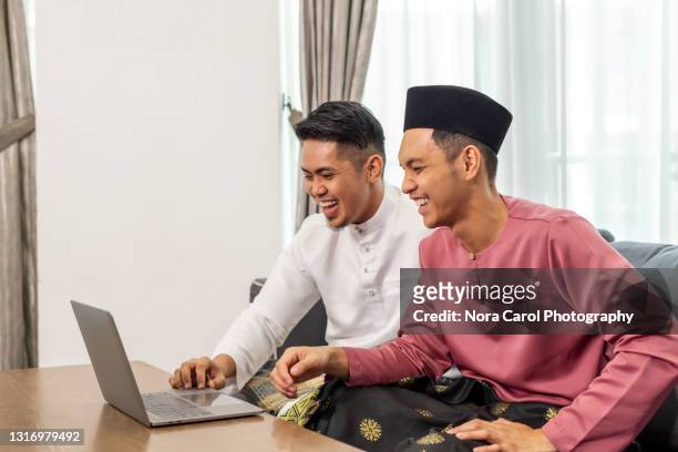 malaysian man with baju melayu using laptop - video conference - handsome muslim men stock pictures, royalty-free photos & images