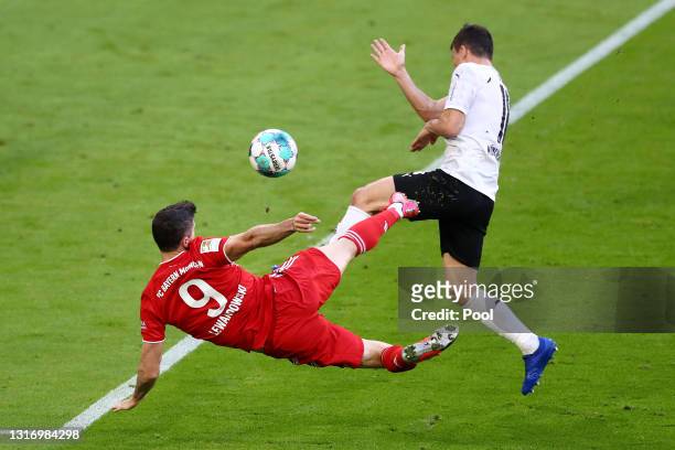 Robert Lewandowski of FC Bayern Muenchen scores their side's third goal whilst under pressure from Stefan Lainer of Borussia Moenchengladbach during...