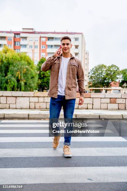 man crossing the street and talking on the phone - pedestrian crossing man stock pictures, royalty-free photos & images