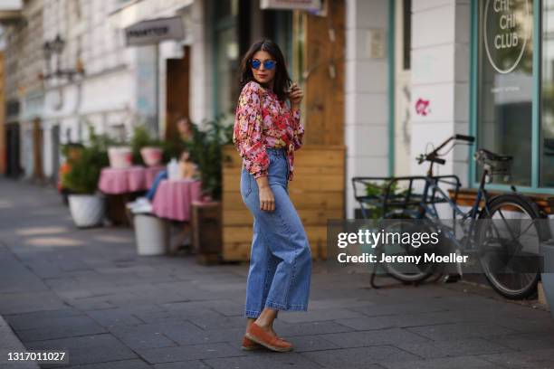 Anna Wolfers wearing colorful floral blouse, sunglasses, blue jeans and orange espadrilles on May 01, 2021 in Hamburg, Germany.