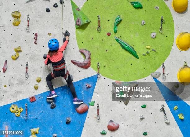 little kid having fun while climbing an artificial wall indoors. - scalata foto e immagini stock
