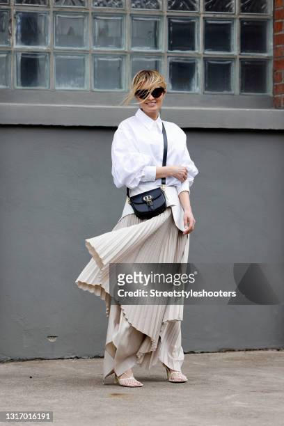 Influencer Gitta Banko, wearing a beige pleated maxi skirt with a white leather belt by Nobi Talai, a white blouse by Nobi Talai, a black bag by...