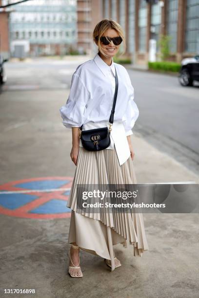 Influencer Gitta Banko, wearing a beige pleated maxi skirt with a white leather belt by Nobi Talai, a white blouse by Nobi Talai, a black bag by...