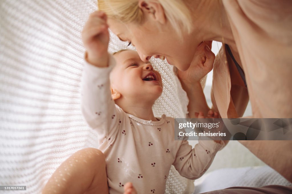 Loving mother and daughter playing under blanket