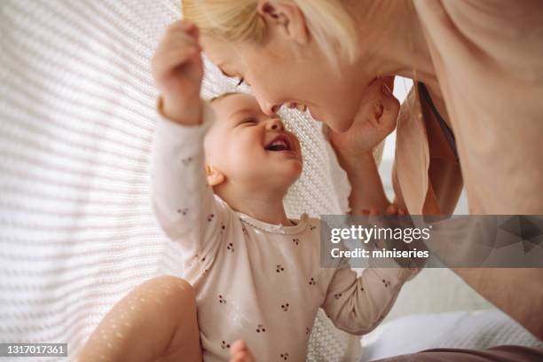 loving mother and daughter playing under blanket - baby imagens e fotografias de stock