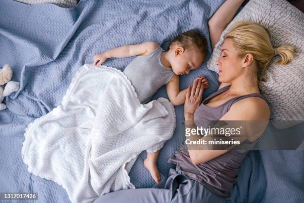 baby flicka som håller hand av mamma medan du sover - mother sleeping baby bildbanksfoton och bilder