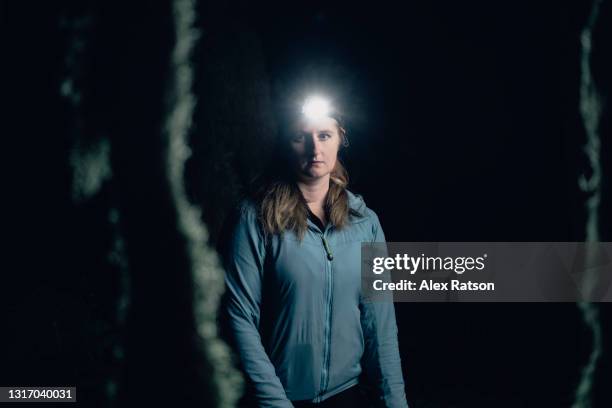 female hiker wears headlamp while walking through forest at night - stirnlampe stock-fotos und bilder