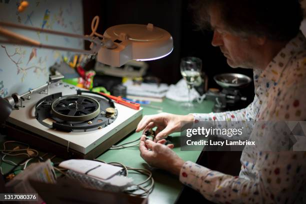 senior man repairing an old turntable at home - plattenspieler stock-fotos und bilder