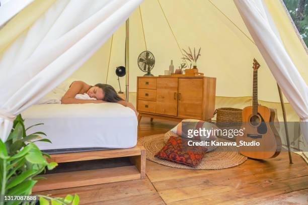 asian woman taking a nap in a luxurious tent - luxury tent stock pictures, royalty-free photos & images