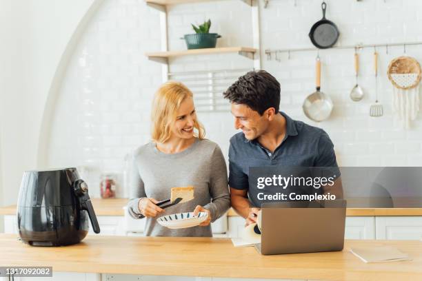 woman working with airfryer and man using laptop - airfryer stock pictures, royalty-free photos & images