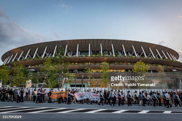 Demonstrators march around the New National Stadium, the main stadium for the Tokyo Olympics, during a protest against the Tokyo Olympics on May 09,...